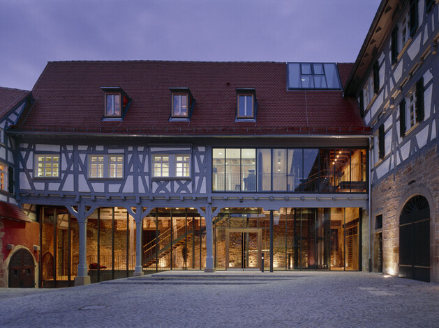 Beleuchtetes Fachwerkgebäude mit großer Glasfront
