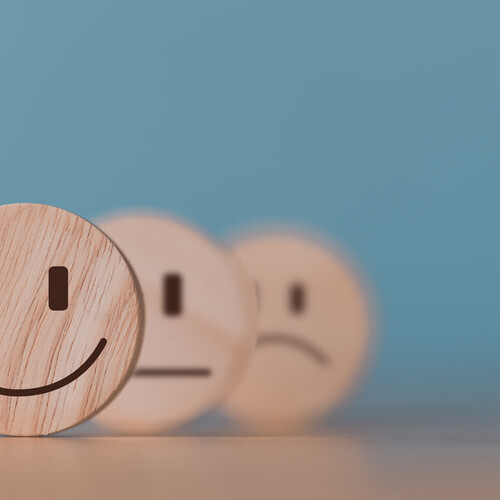 Bild von drei Holzmünzen mit lachenden, neutralen und traurigen Emojis Header_Feedback.jpg