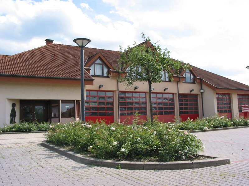 Feuerwehrhaus; im Vordergrund Parkplätze und Grünfläche