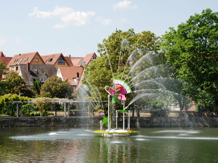 Die Skulptur "Enzblume" in der Enz; im Hintergrund die Bietigheimer Altstadt