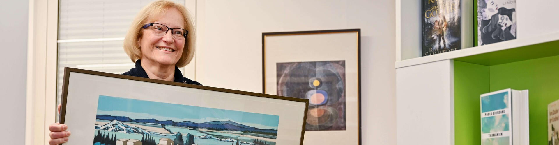 lächelnde Frau hält ein Kunstwerk hoch Header_Artothek.jpg