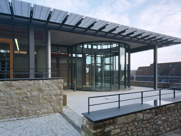 Gebäude mit Glasfront und einer Steinmauer davor