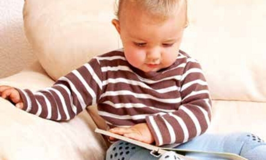 Baby mit aufgeblättertem Buch auf Couch