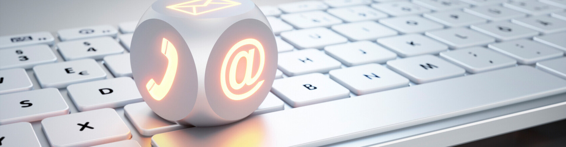 Ein Würfel mit einem Telefon- und einem Mailsymbol liegt auf einer Tastatur header-kontakt.jpg